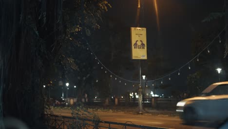 -Night-Traffic-on-an-Indian-city-road-with-vehicles,-Peoples-walking-on-the-road-sidewalk-and-cars-driving-on-the-highway