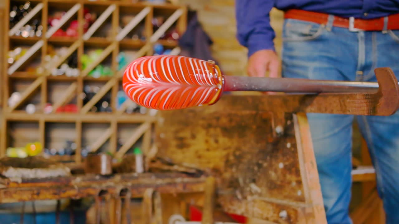 Anziano uomo scandinavo che lascia raffreddare un'opera d'arte in vetro, creando la forma del prodotto finito. Splendido vetro artistico, creato e lavorato in una fornace vetraria incandescente, come installazione artistica temporanea, mediante soffiatura.