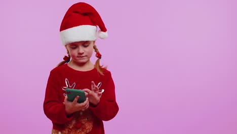 Girl-toddler-in-Christmas-Santa-hat-with-mobile-phone-showing-pointing-empty-place,-advertising-area