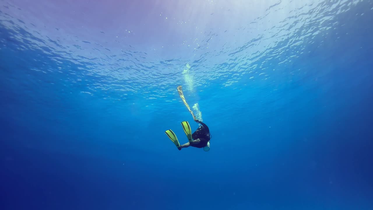 Diver filling and using a Surface Marking Tube during a safety stop. Mnemba Island, Zanzibar, Tanzania.