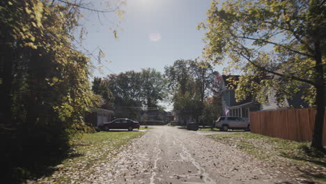 drive along a typical street of an american town on a clear autumn day. back window view