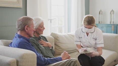 female doctor with mask makes home visit to senior couple for medical check during covid-19 lockdown