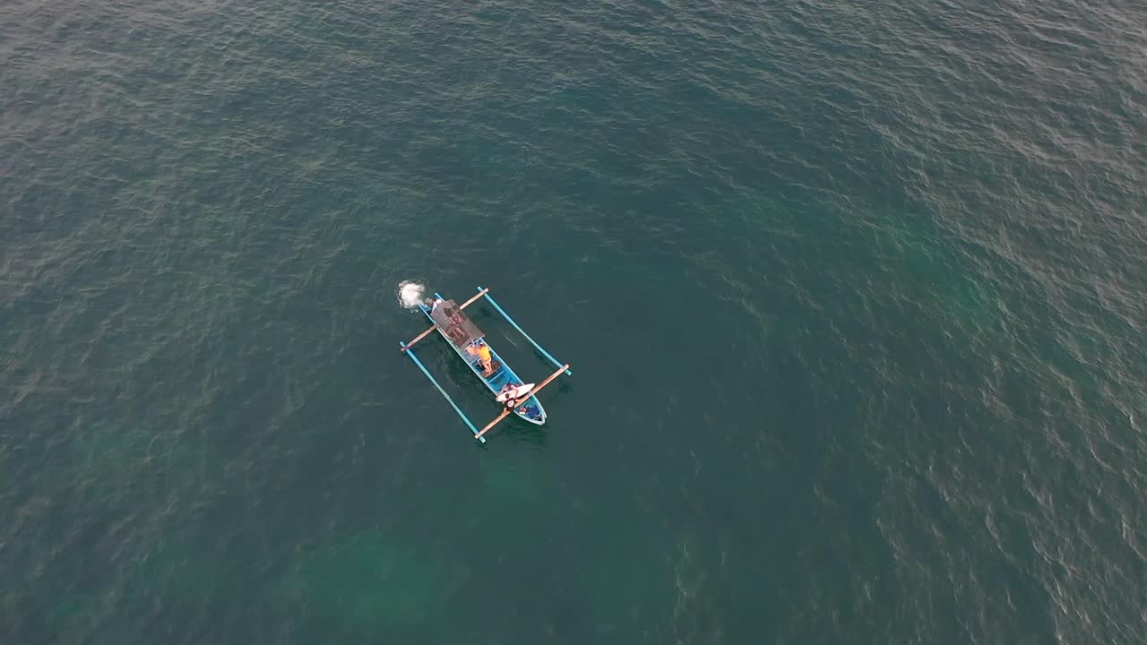 전통적인 발리 보트에서 서핑 보드를 타고 항해하는 서퍼