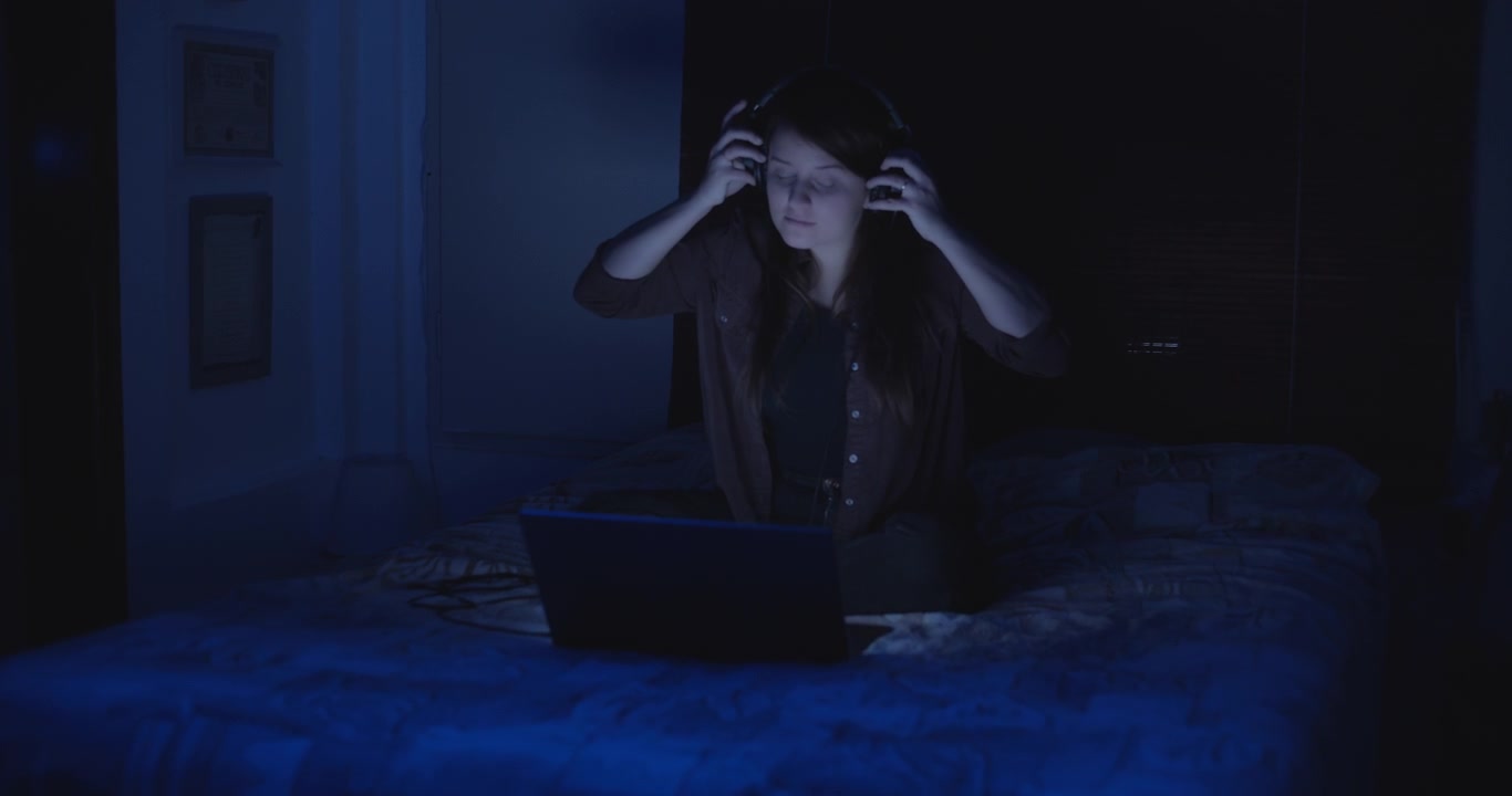 Woman puts the headphones on at night