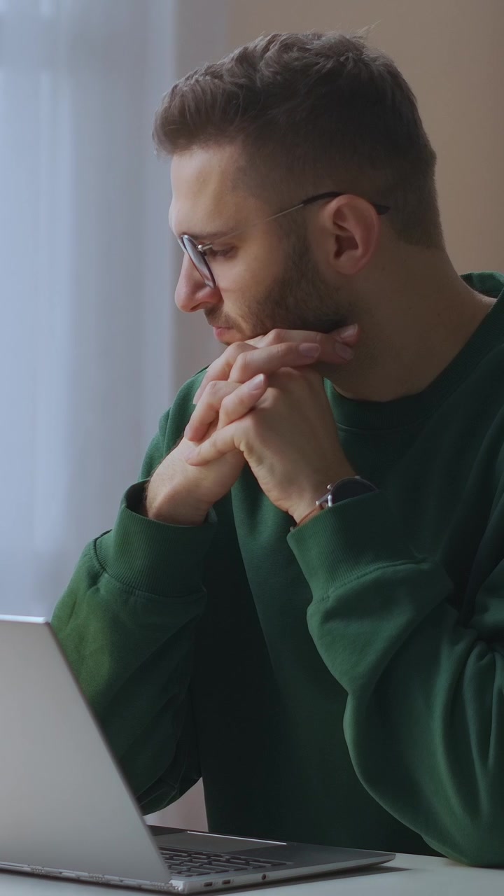 Giovane uomo concentrato che lavora e riflette al laptop