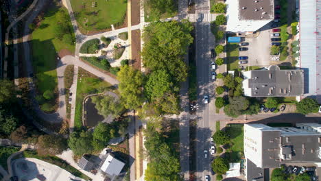 Aerial-view-of-Park-Centralny,-the-bustling-downtown-park-in-Gdynia,-with-buildings-and-cars-passing-by-on-the-streets-below