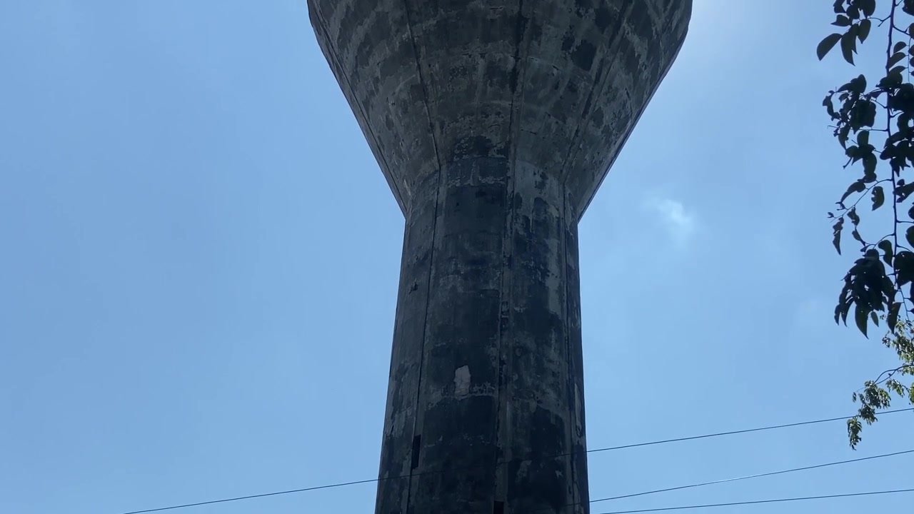 Alta torre dell'acqua in cemento contro un cielo azzurro limpido