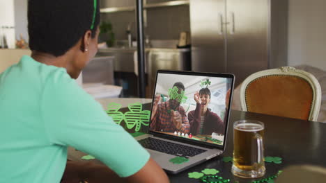 pareja sonriente y diversa que usa artículos en forma de trébol en una videollamada en una computadora portátil