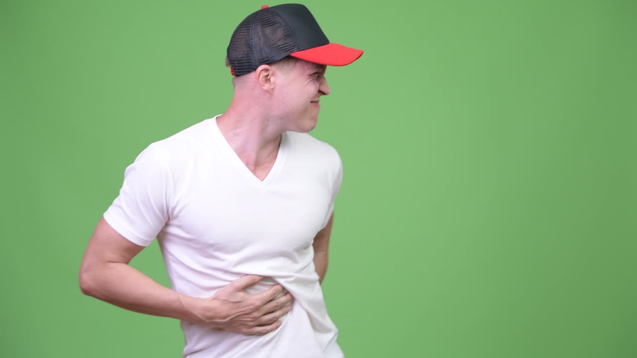 Young handsome Scandinavian man having stomach ache against green background