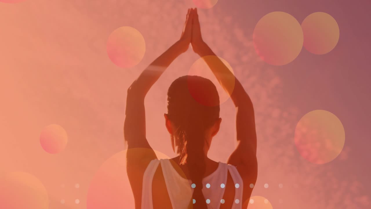 Praticante di yoga che alza le braccia in posizione di preghiera sotto un cielo luminoso con bagliori fluttuanti per il benessere.