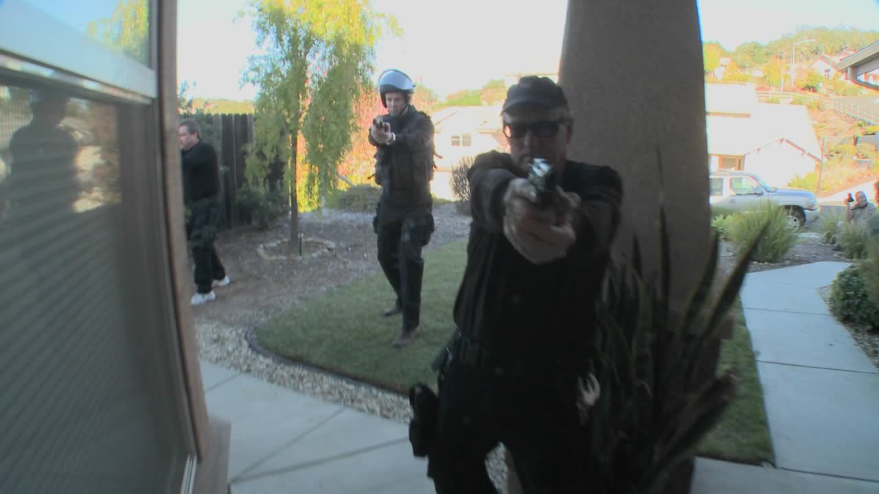 oficiales de la dea o swat con los brazos en alto golpean la puerta antes de realizar un allanamiento de drogas en una casa 1