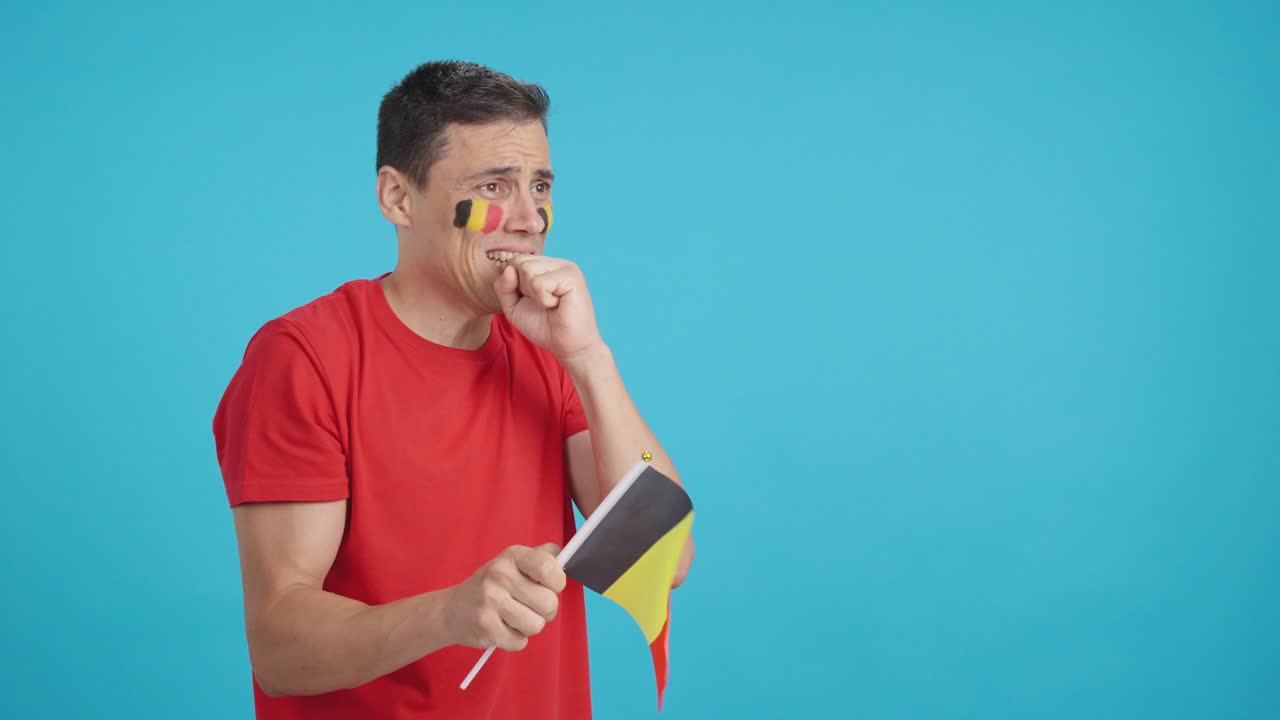 Nervous man cheering for Belgium during a match looking away