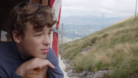 teenage boy contemplating mountain view from train