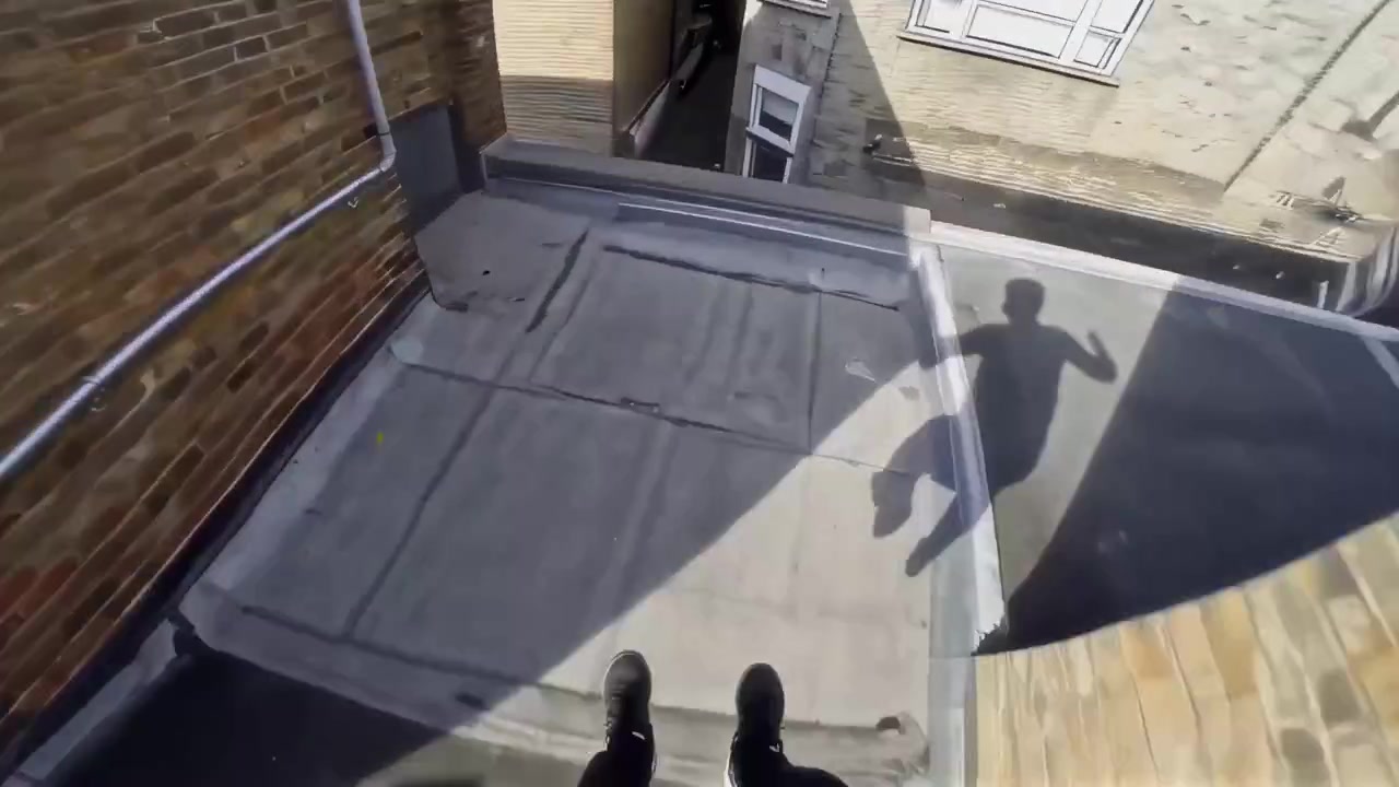 Atleta di parkour che salta da un tetto in un ambiente urbano