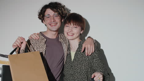 una joven pareja alegre posando con bolsas de compras en el estudio