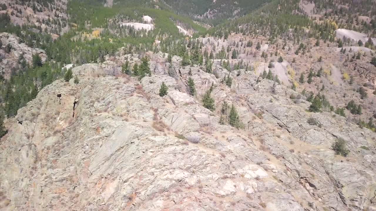 배경에 활기찬 녹색과 노란색 나무가 있는 바위 산 정상의 트럭 항공, 은색 깃털 콜로라도의 4k