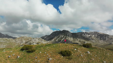 back of woman on hilltop in front of majestic montenegro mountains; drone reveal