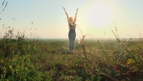 woman practicing yoga in a field at sunrise