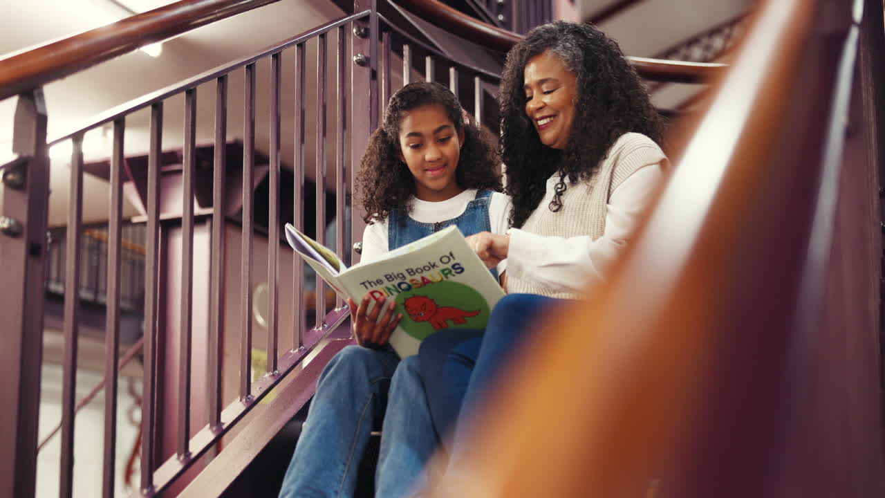 Avó e neta lendo um livro juntas nas escadas