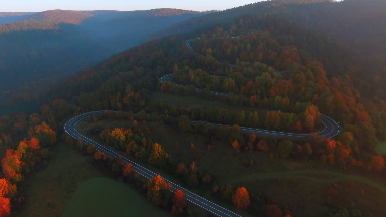 vista aérea de un camino sinuoso a través de un colorido bosque de otoño