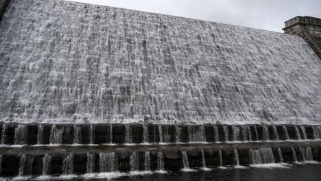 Water-cascades-over-the-weir-at-Fernworthy-Reservoir-Dam-in-Dartmoor-National-Park,-Devon,-England