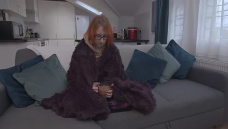 Sad-depressed-woman-sits-on-sofa-with-mug-of-tea