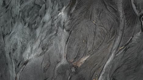 aire arriba abajo lecho del río río glacial que fluye a través de paisaje volcánico natural negro