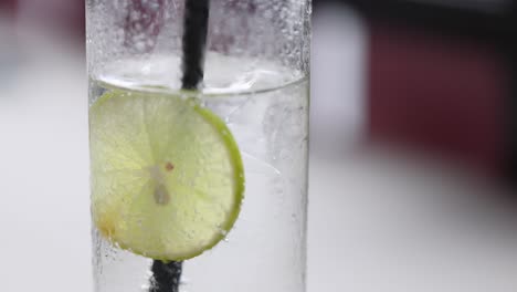 primer plano de una rodaja de limón en agua con gas, destacando la condensación y las burbujas en un entorno de bebida refrescante