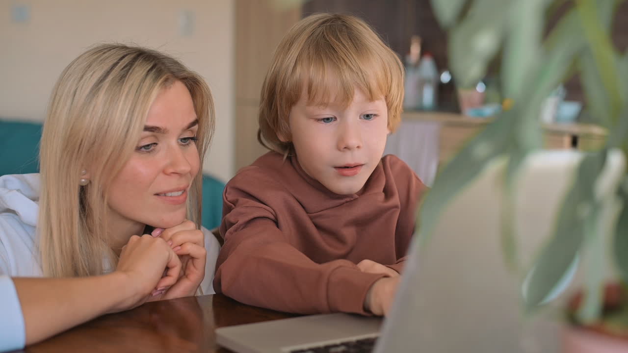 ragazzino e madre che guardano il computer portatile e si divertono a casa