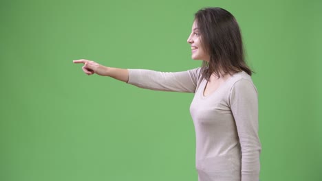 Profile view of young happy beautiful woman against green background