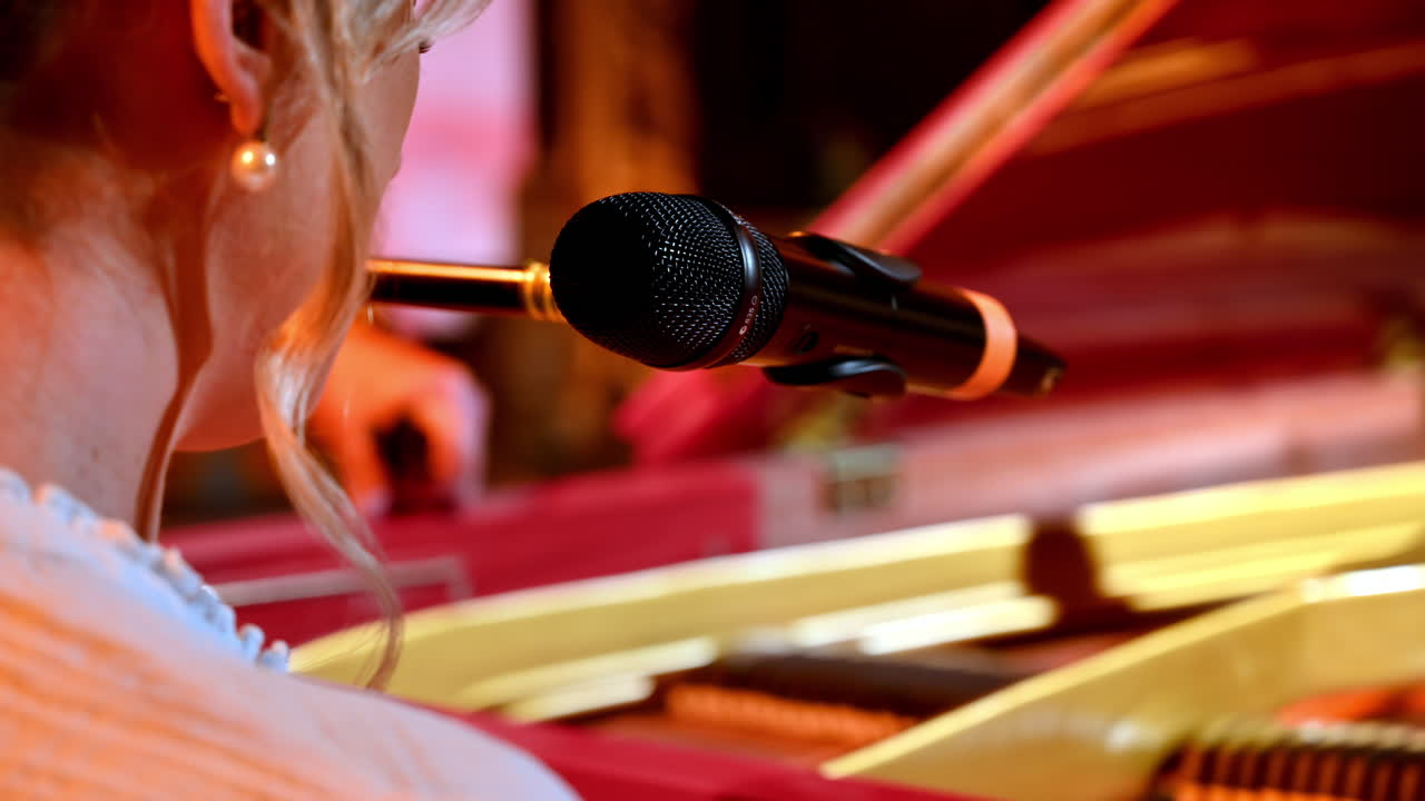 Woman singing into the microphone and playing a red piano