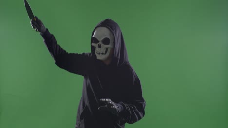 scary man in the hooded sweatshirt wearing halloween mask stabbing with a knife for making threatening gesture on the green screen background