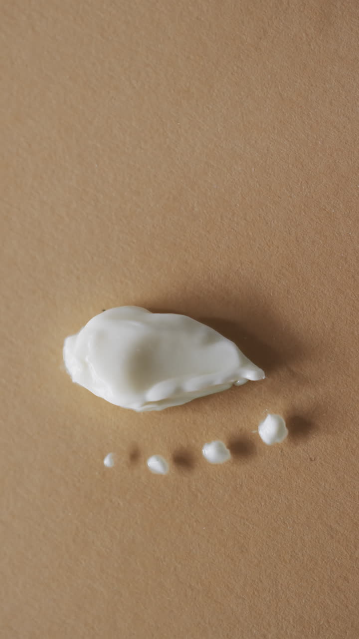 Vertical video of beauty product cream smudges with copy space on brown background