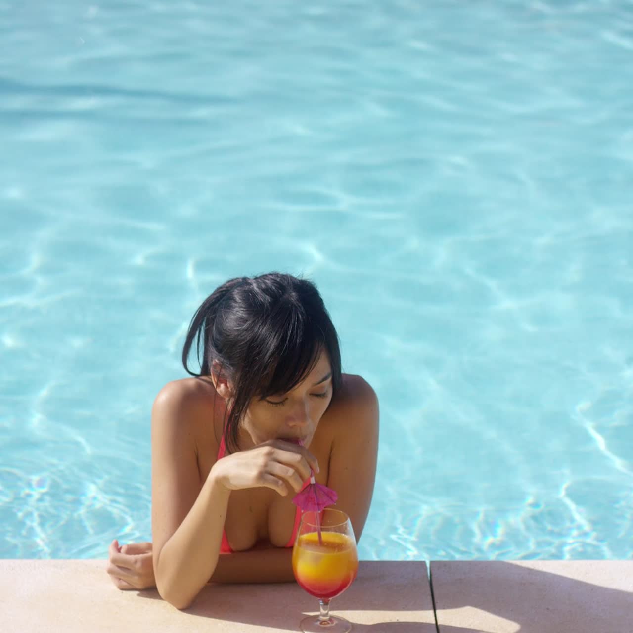 Donna serena a bordo piscina con un drink
