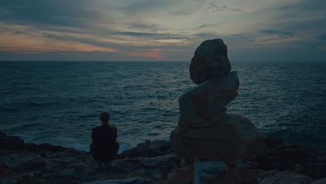 woman watching sunset over the ocean with rocks