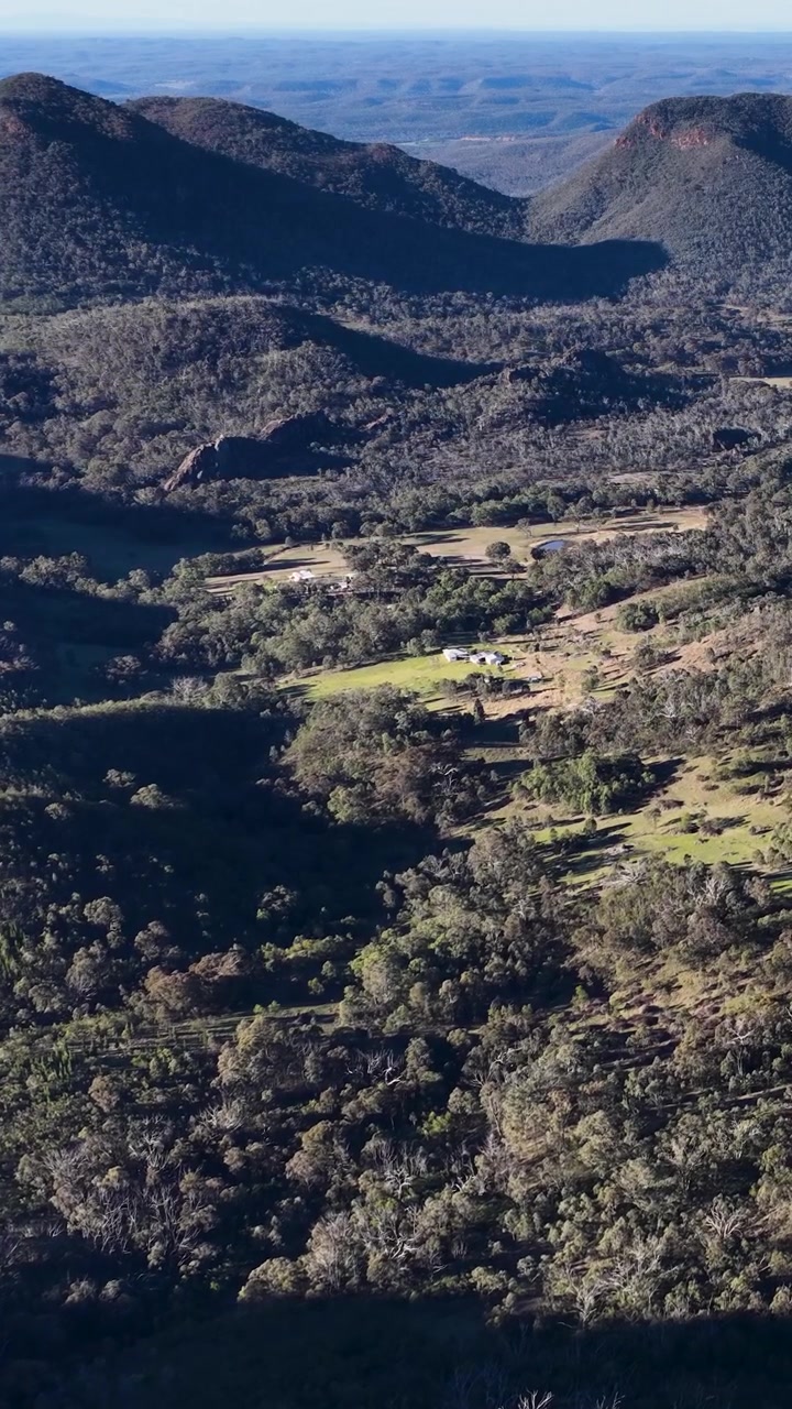 Ampia ripresa aerea di montagne aspre e foreste di eucalipto nel Parco Nazionale Warrumbungle, Australia.