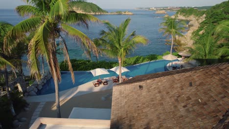 Luftaufnahme-Durch-Palmen-Des-Luxuriösen-Hotels-Mit-Pool-An-Den-Stränden-Von-Huatulco