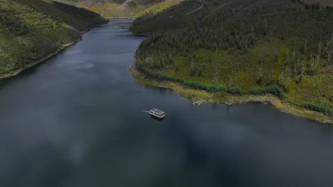 vista aérea de un barco navegando a lo largo de valles de pinos con un impresionante reflejo del cielo en el agua