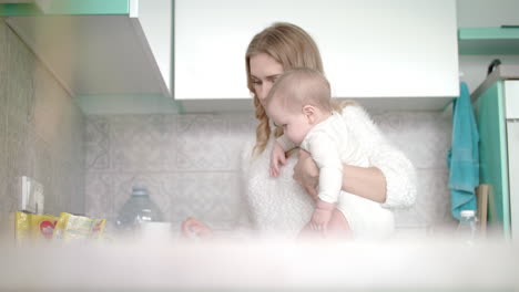 woman with baby preparing food on kitchen. mom cooking oatmeal for little kid