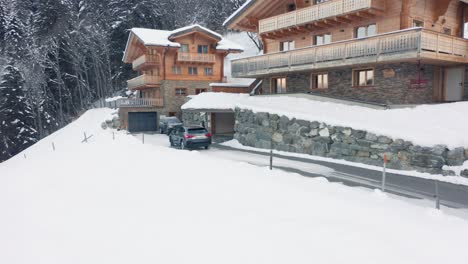 Car-driving-into-parking-garage-of-beautiful-chalet-in-a-snow-covered-rural-landscape