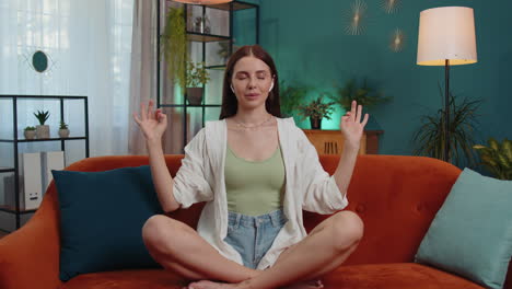 woman breathes deeply with mudra gesture, eyes closed meditating with concentrated thoughts peaceful