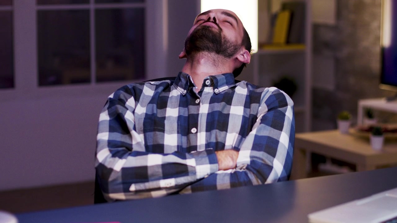 Exhausted Man Resting at Desk in Home Office at Night