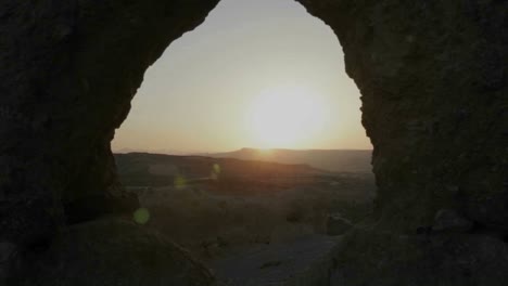 The-sun-is-seen-rising-through-a-cave-and-above-overlapping-mountains