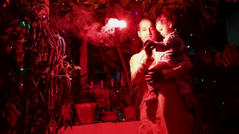 father and son celebrating diwali by burning sparkler at night from different angle