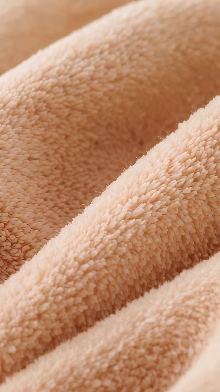 Video verticale: cambio di camera che rivela da vicino le pieghe di un tessuto felpato color beige pesca, che ne mostra la texture