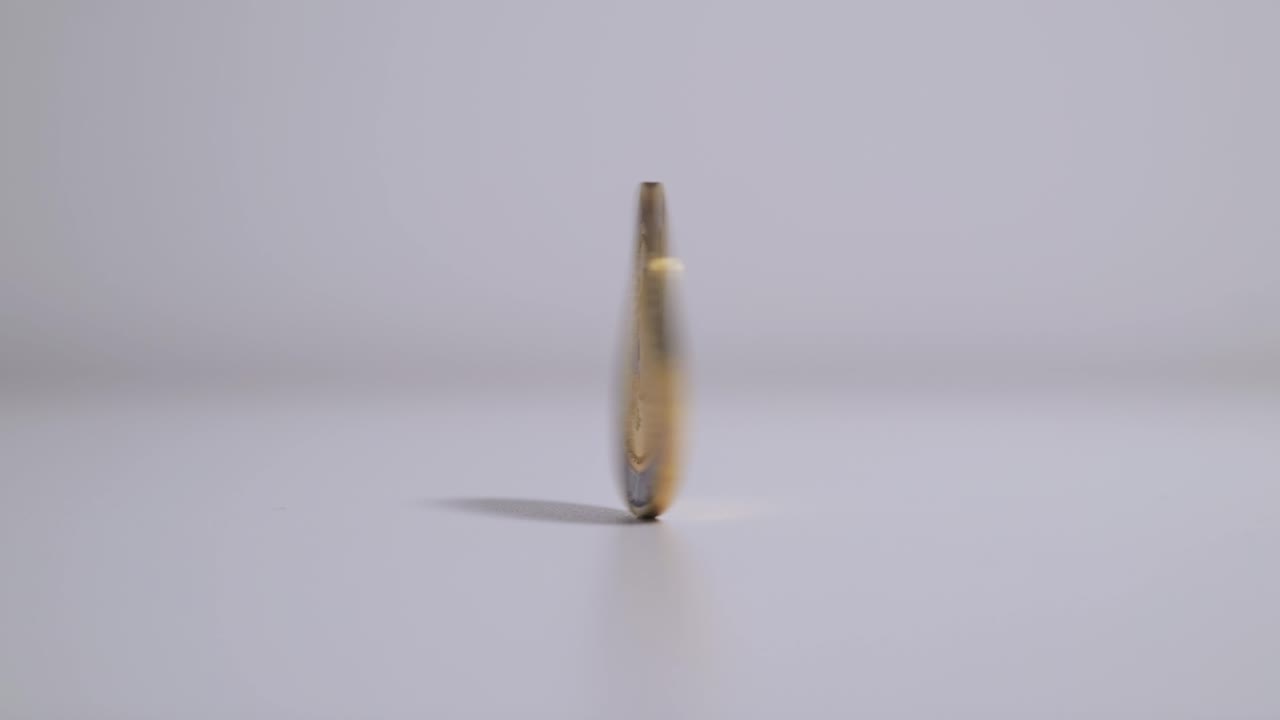 Coin spinning on table after finger flick, close up slow motion static frame