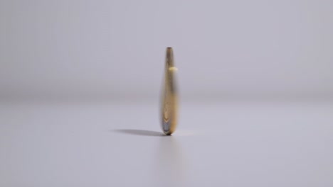 coin spinning on table after finger flick, close up slow motion static frame