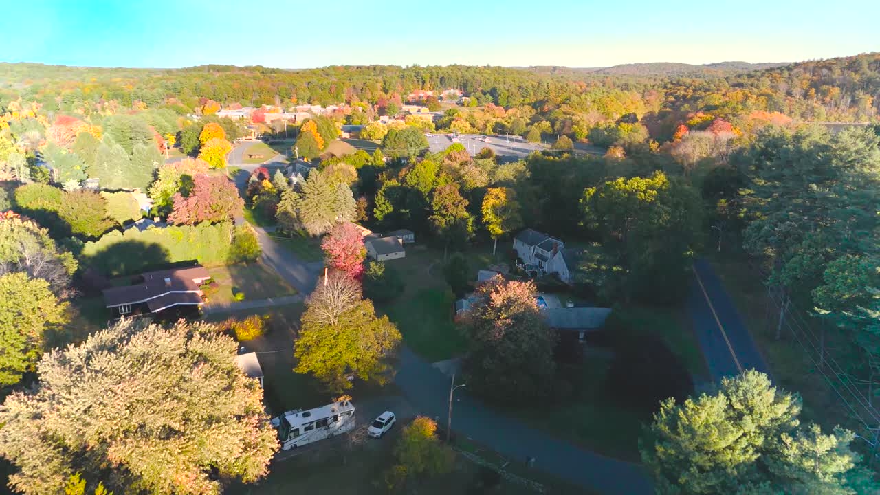 A captivating drone shot circling a Massachusetts pond in autumn, highlighting the stunning fall foliage and serene water reflections. found in New England.