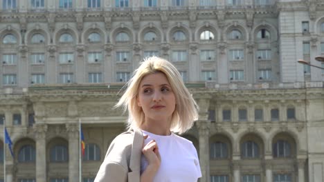 young blonde girl in a white t-shirt waiting for someone, palace of the parliament in the background, bucharest romania