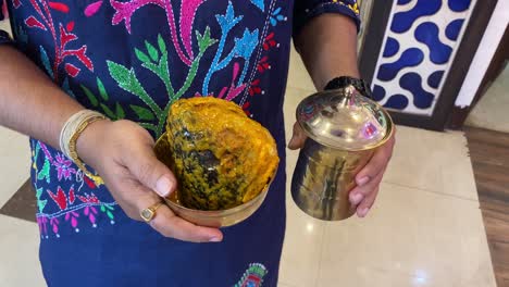 A-man-holding-the-head-of-the-fish-in-golden-color-bowl-in-a-Bengali-ceremony-in-Kolkata